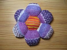 a knitted flower sitting on top of a wooden table