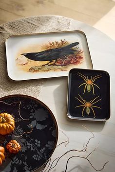 two plates with halloween decorations on them and one has a bird, spider, and pumpkins