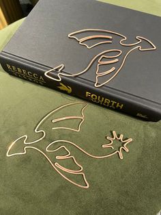 a book sitting on top of a green table next to a black and gold cover