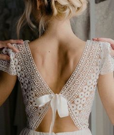 the back of a woman's dress with white crochet and ribbon on it