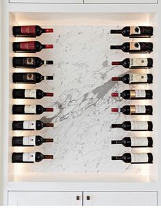 a wall mounted wine rack filled with lots of bottles on top of a white counter