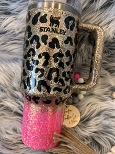 a pink and black leopard print coffee cup with the words stand on it, sitting on a furry surface