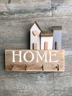 a wooden sign that says home with two small houses on it and a heart in the middle