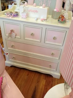 a white dresser with pink drawers and decorations on it's top, next to a baby crib