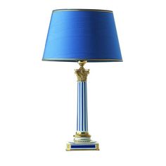 a blue and gold lamp with a blue shade on the top, sitting next to a white wall