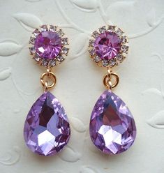 This is a statement earrings. Elegant, opulent, and shimmery, this show stopping earrings feature a rich palate. This brilliant classic earrings features purple Swarovski crystals. Crystals are set on a secure prong settings, made of brass and plated in 18 karat gold.. These earrings have surgical steel posts and measure 1.25" in length. These luxury earrings are bold and beautiful, and make a powerful statement. These stunning dangle earrings are unique, feminine and eye-catching, Perfect for a Glamorous Purple Drop Earrings, Purple Crystal Earrings For Wedding, Purple Crystal Drop Earrings For Evening, Purple Drop Crystal Earrings For Evening, Purple Teardrop Crystal Earrings For Wedding, Lavender Crystal Earrings For Wedding, Elegant Lavender Crystal Earrings For Party, Elegant Lavender Crystal Earrings For Wedding, Elegant Purple Crystal Earrings For Evening