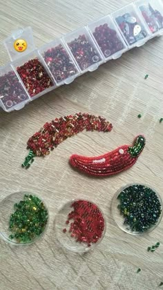 beaded christmas ornaments in plastic containers on a table with other beads and decorations around them