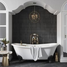 a white bath tub sitting under a chandelier in a bathroom