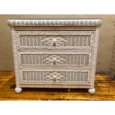 a white wicker dresser with drawers on top