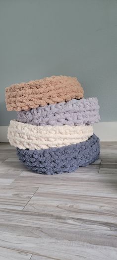 a stack of towels sitting on top of a wooden floor in front of a wall