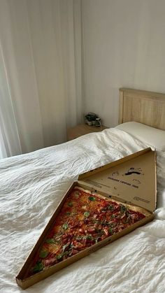 an open pizza box sitting on top of a bed next to a white comforter