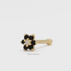 a gold ring with black and white flowers on it's side, sitting on a white surface