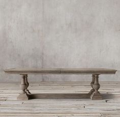 an old wooden table sitting on top of a hard wood floor next to a wall