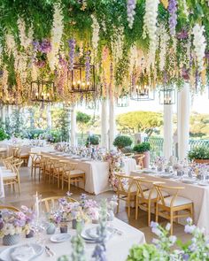 an outdoor dining area with tables, chairs and flowers hanging from the ceiling