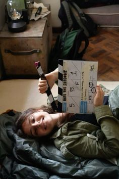 a woman laying on top of a bed while holding a remote control in her hand