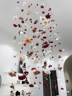 a room filled with lots of white and red flowers flying from the ceiling to the floor