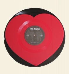 a red and black heart shaped record with the beatles logo on it's side