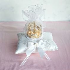 a small glass vase sitting on top of a white pillow covered in ribbon and bow