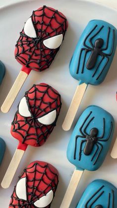 spiderman lollipops are sitting on a white plate with blue and red pops