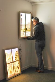 a man standing in front of a window looking at the light coming from inside it