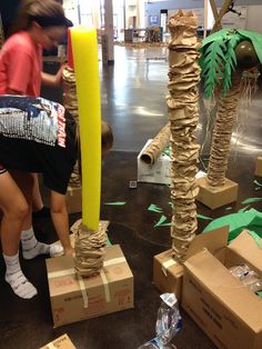 a woman standing next to cardboard boxes with palm trees on them and other items in front of her