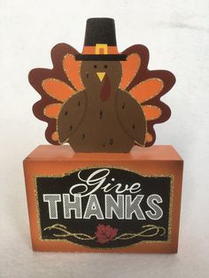 a cardboard turkey with a pilgrim hat on it's head and give thanks sign