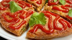 a white plate topped with pizza covered in ketchup and green leafy garnish