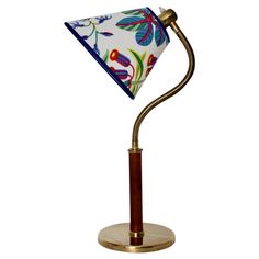 a desk lamp with a white and blue flowered shade on it's side