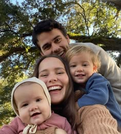 a man, woman and child are smiling for the camera with trees in the background