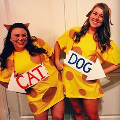 two women dressed in costumes standing next to each other holding signs that say cat and dog