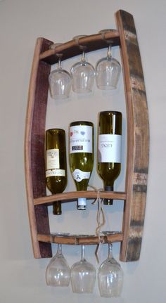 wine glasses and bottles are hanging from a wooden rack with three wine glasses on it