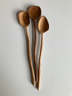 three wooden spoons are lined up on a white surface