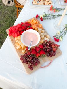 an assortment of fruits and dip on a cutting board