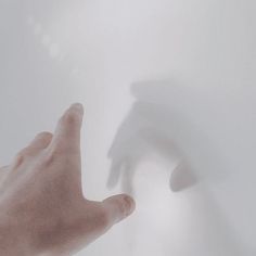 a person's hand reaching for something in the air with their shadow on the wall