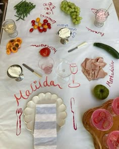 a table topped with lots of food on top of a white table covered in utensils