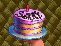 a hand holding a birthday cake with the word sorry written on it