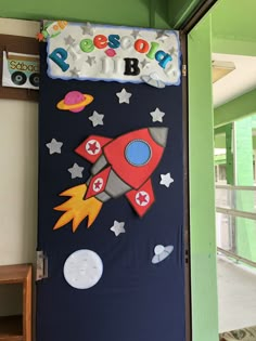 a door decorated with an outer space theme and name on it, in the shape of a rocket ship