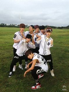 a group of young men standing next to each other on top of a lush green field