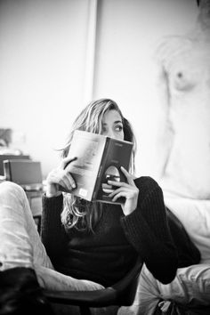 a woman sitting in a chair reading a book