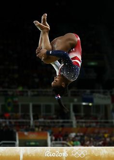 a woman doing a handstand on the balance beam