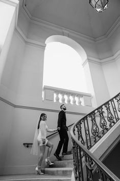 a bride and groom walking down the stairs at their wedding reception in black and white