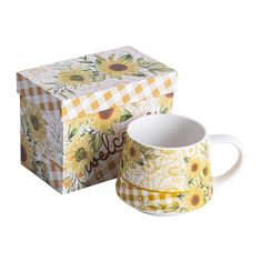 a yellow and white coffee mug sitting in front of a box with sunflowers on it