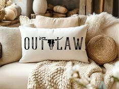 a pillow with the word out law printed on it sitting on a couch next to pillows