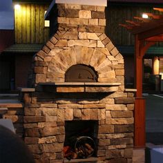 an outdoor brick pizza oven built into the side of a building with a gazebo in the background