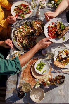 several people sitting at a table with plates of food