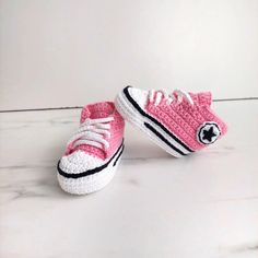 two crocheted pink and white sneakers on a marble surface with the word converse written in black