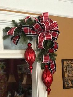 a red and black bow hanging from the side of a door with christmas decorations on it