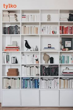 a bookshelf filled with lots of books on top of white shelves next to a wooden floor