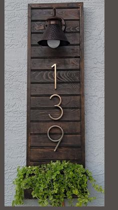 a house number sign mounted to the side of a building with a lamp on it