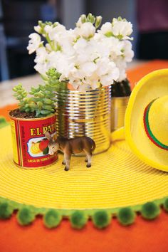 a tin can with flowers and a small toy horse in it on top of a table